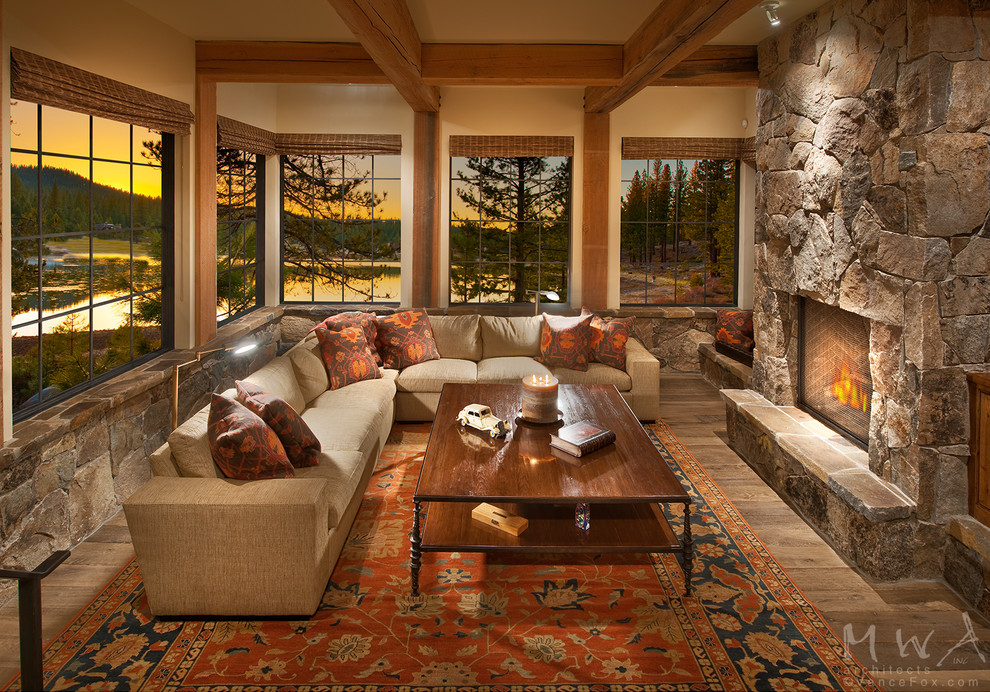Inspiration for a large country open concept family room in Other with beige walls, medium hardwood floors, a standard fireplace, a stone fireplace surround and brown floor.