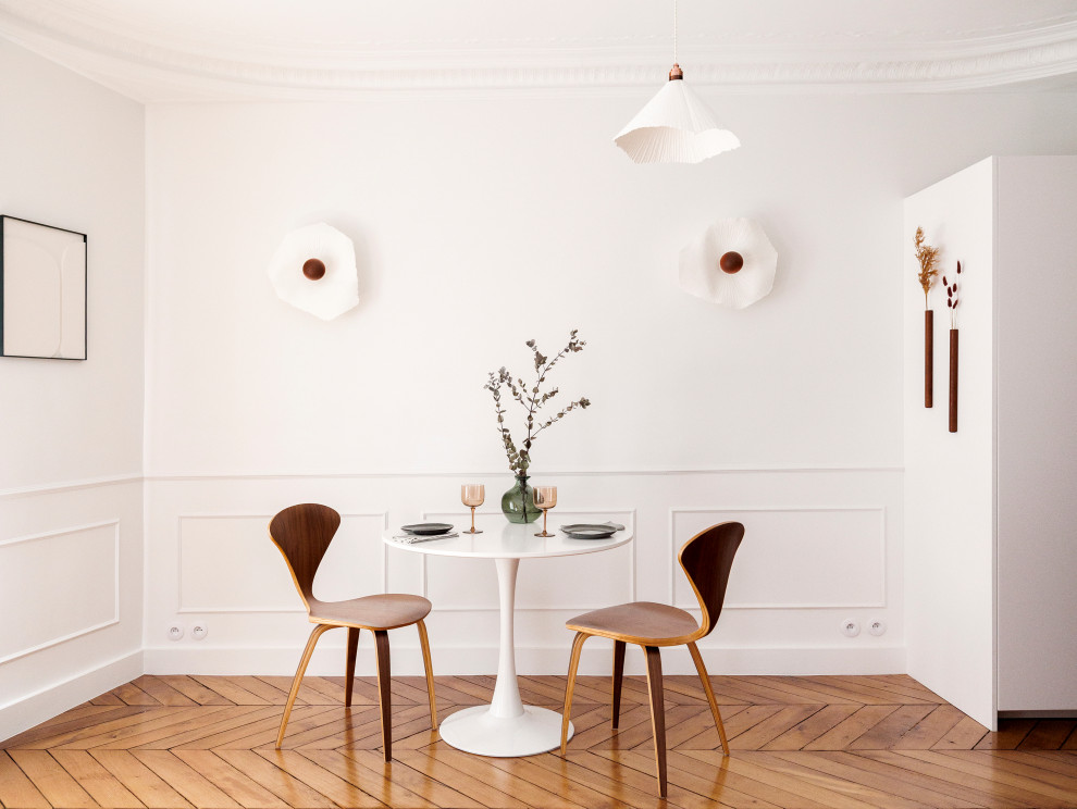 Cette image montre une salle à manger ouverte sur le salon traditionnelle de taille moyenne avec un mur blanc, parquet clair, un plafond décaissé, boiseries et éclairage.