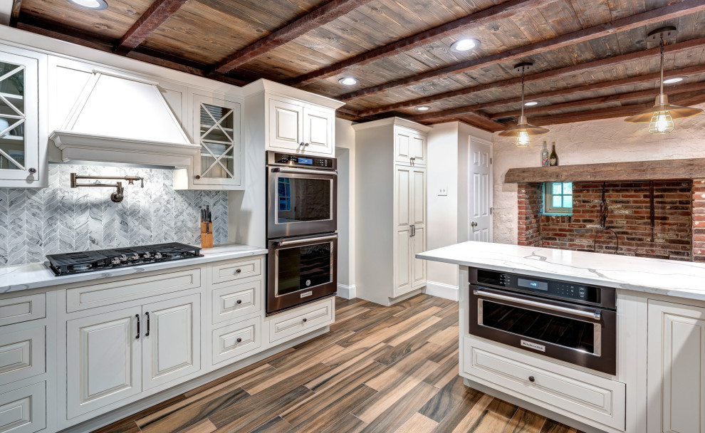 This is an example of an expansive country u-shaped separate kitchen in Philadelphia with a farmhouse sink, raised-panel cabinets, white cabinets, quartz benchtops, blue splashback, mosaic tile splashback, stainless steel appliances, porcelain floors, a peninsula, multi-coloured floor and multi-coloured benchtop.