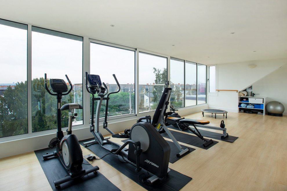 Large contemporary multi-use home gym in London with white walls, laminate floors and yellow floors.