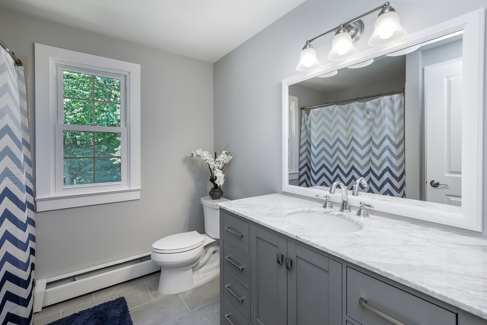 Design ideas for a mid-sized traditional bathroom in Cleveland with shaker cabinets, grey cabinets, an alcove tub, a shower/bathtub combo, a one-piece toilet, white walls, an undermount sink, grey floor, a shower curtain and white benchtops.