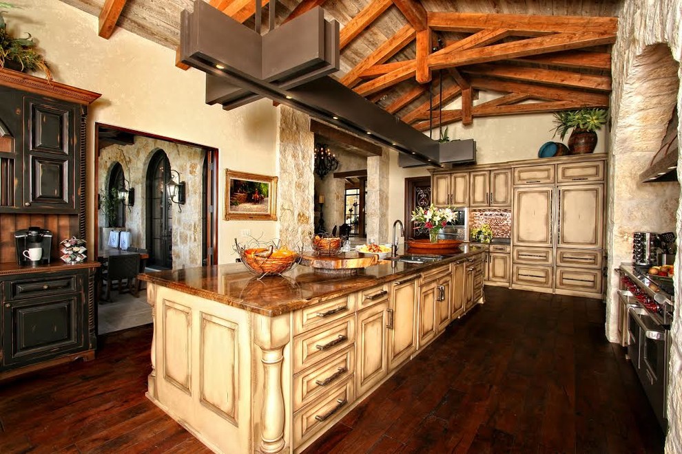 Kitchen - large rustic l-shaped dark wood floor and brown floor kitchen idea with a double-bowl sink, raised-panel cabinets, distressed cabinets, granite countertops, paneled appliances and an island