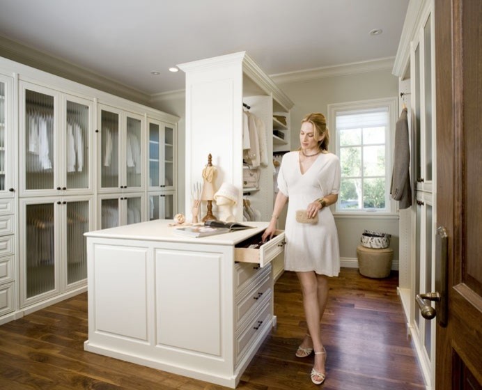 Inspiration for a large traditional gender-neutral walk-in wardrobe in Montreal with glass-front cabinets, white cabinets and medium hardwood floors.