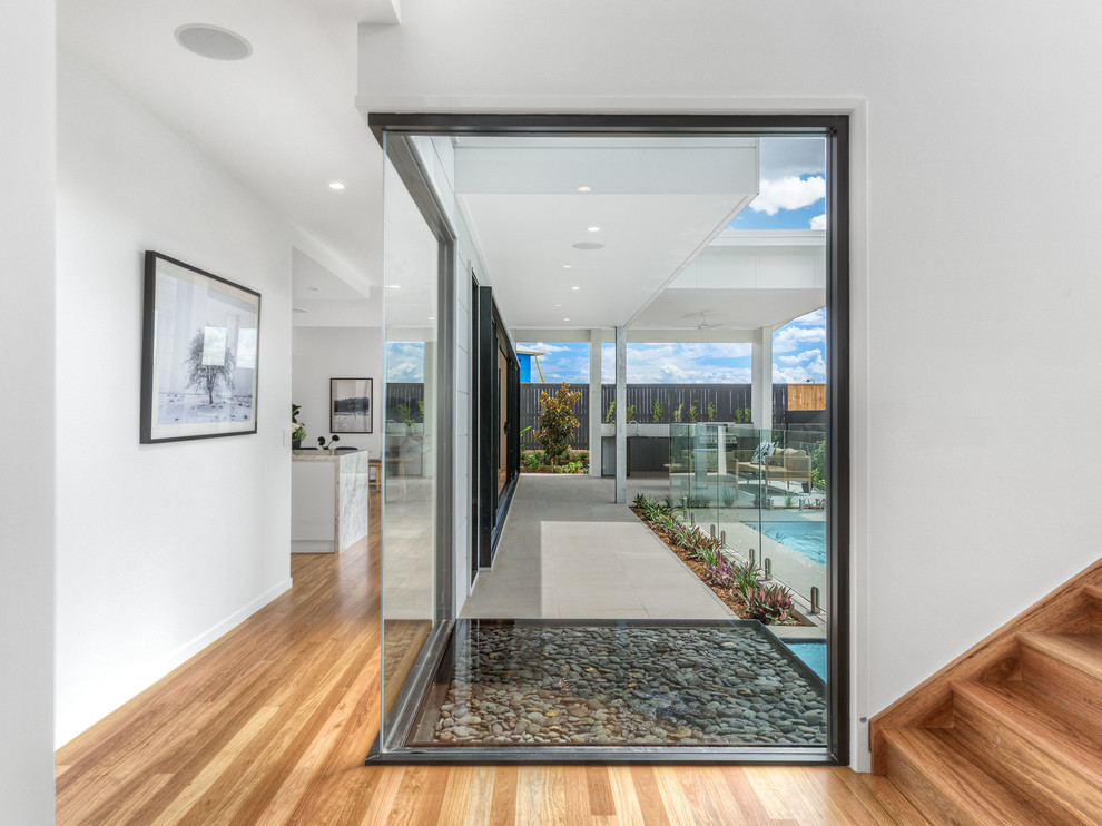 Contemporary hallway in Brisbane with white walls and medium hardwood floors.