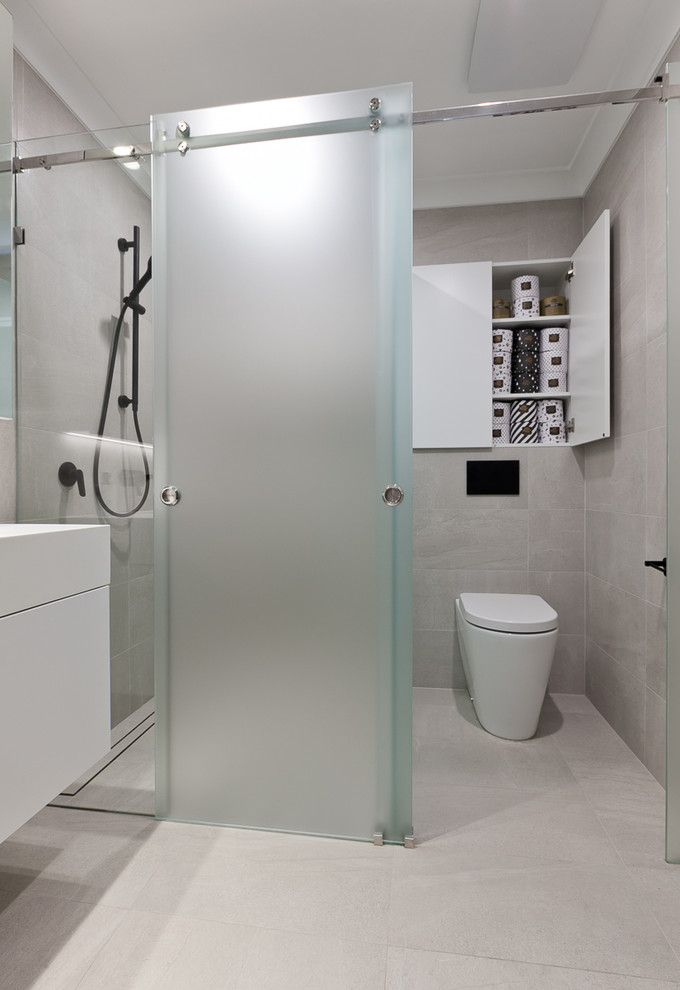 Small contemporary 3/4 bathroom in Perth with flat-panel cabinets, white cabinets, a two-piece toilet, beige tile, porcelain tile, beige walls, porcelain floors, an integrated sink, solid surface benchtops, beige floor, a sliding shower screen and white benchtops.