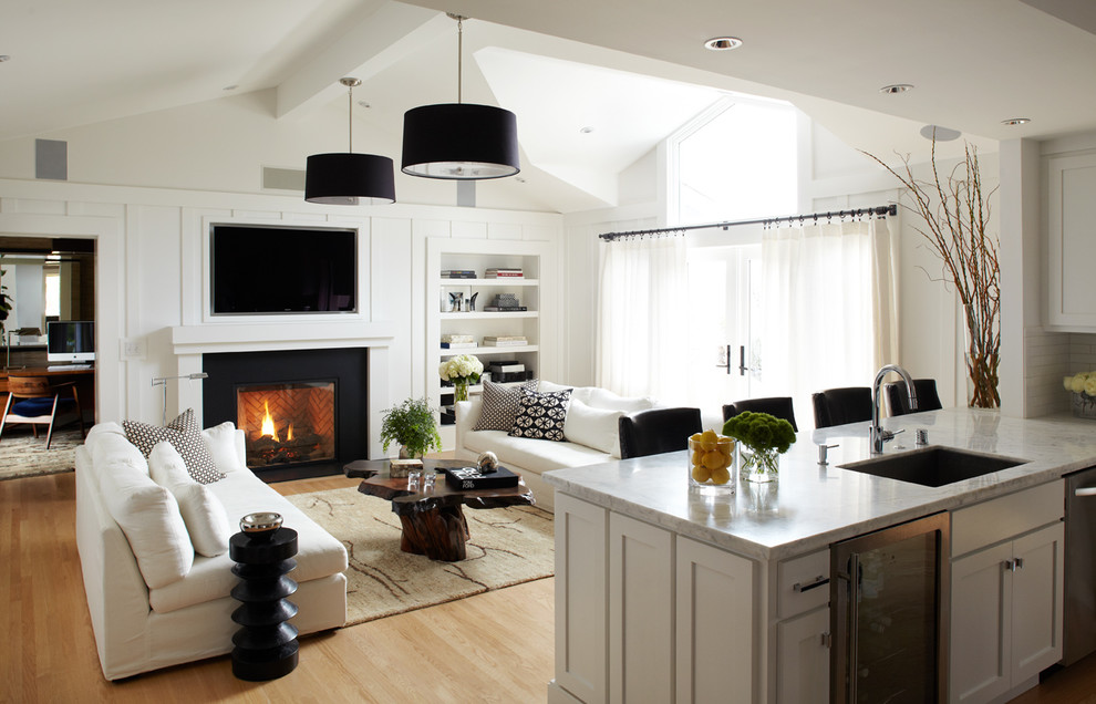 Transitional open concept living room in San Francisco with white walls, a standard fireplace, a wall-mounted tv and light hardwood floors.