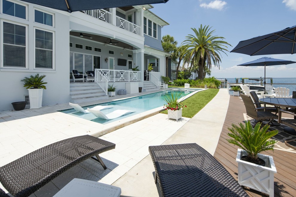 Photo of a large beach style backyard rectangular lap pool in Tampa with a hot tub and concrete pavers.