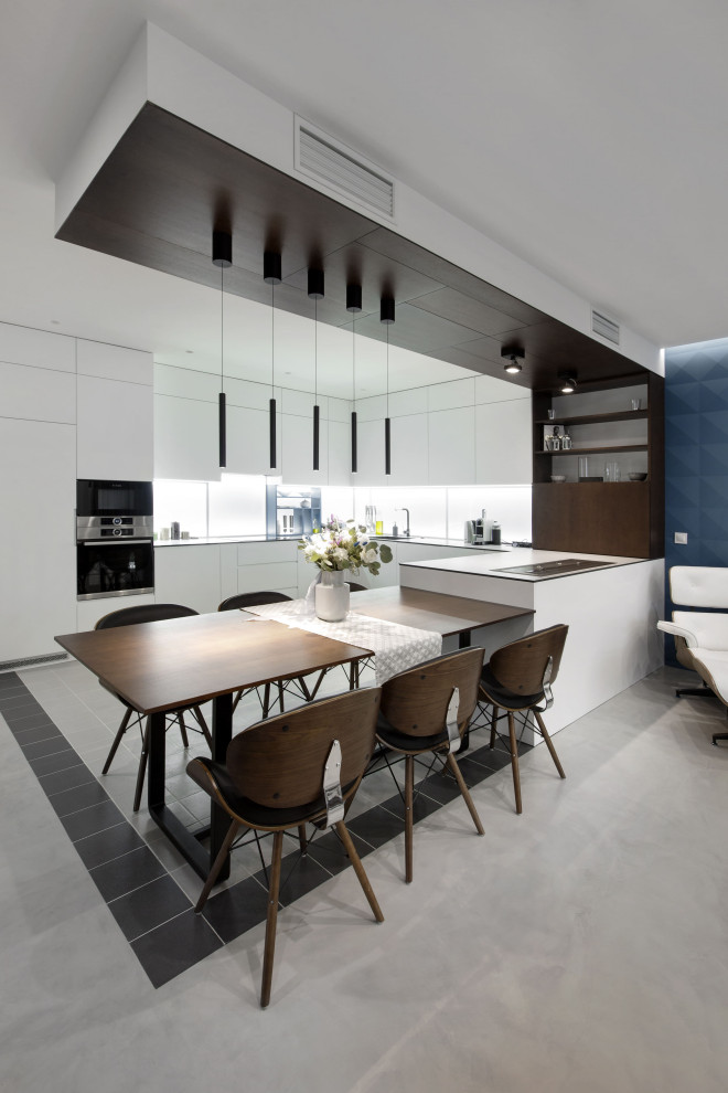 Expansive contemporary u-shaped eat-in kitchen in Other with a drop-in sink, flat-panel cabinets, white cabinets, white splashback, panelled appliances, a peninsula, grey floor and white benchtop.