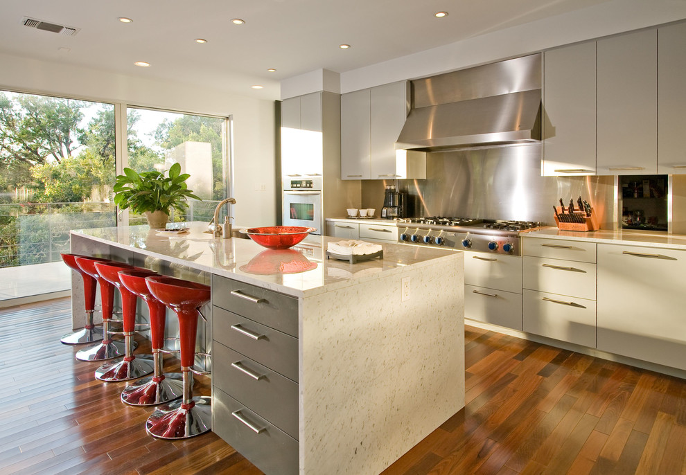 Design ideas for a contemporary l-shaped open plan kitchen in Austin with flat-panel cabinets, grey cabinets, metal splashback, stainless steel appliances, metallic splashback, an undermount sink and marble benchtops.