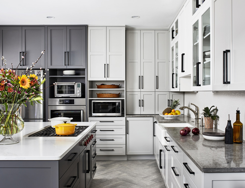 Photo of a large transitional open plan kitchen in DC Metro with a farmhouse sink, grey cabinets, white splashback, stainless steel appliances, with island, grey floor and grey benchtop.