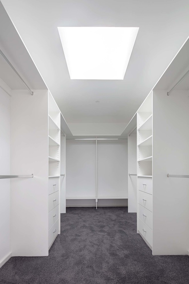 Large contemporary gender-neutral walk-in wardrobe in Melbourne with carpet.