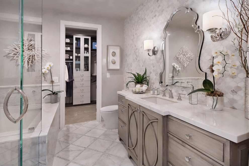 Design ideas for a mid-sized transitional master bathroom in Orange County with raised-panel cabinets, grey cabinets, an undermount tub, a corner shower, a two-piece toilet, grey walls, marble floors, an undermount sink, marble benchtops, grey floor and a hinged shower door.