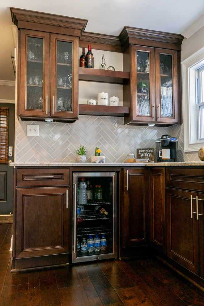 Inspiration for a mid-sized transitional eat-in kitchen in Atlanta with an undermount sink, shaker cabinets, brown cabinets, granite benchtops, grey splashback, subway tile splashback, black appliances, dark hardwood floors, with island, brown floor and multi-coloured benchtop.