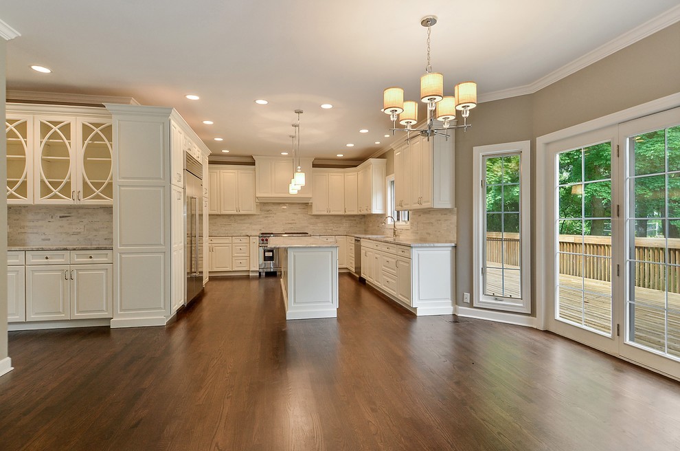 Inspiration for a transitional dark wood floor eat-in kitchen remodel in Chicago with a drop-in sink, raised-panel cabinets, white cabinets, marble countertops, gray backsplash, ceramic backsplash, stainless steel appliances and an island
