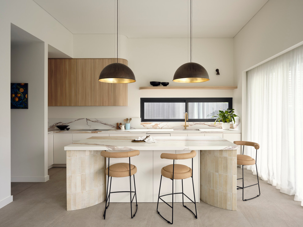 This is an example of a large contemporary l-shaped open plan kitchen in Sydney with with island, an undermount sink, flat-panel cabinets, white cabinets, beige splashback, grey floor and beige benchtop.