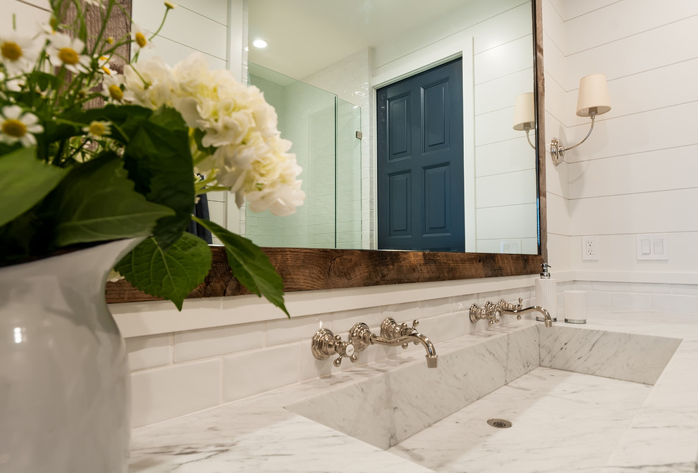 Photo of a country 3/4 bathroom in San Diego with recessed-panel cabinets, white cabinets, white walls, cement tiles, a trough sink, marble benchtops, beige floor and grey benchtops.