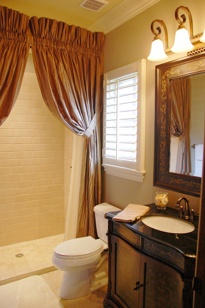 Mid-sized mediterranean 3/4 bathroom in Orlando with an undermount sink, an alcove shower, a two-piece toilet, furniture-like cabinets, black cabinets, quartzite benchtops, white tile, ceramic tile, beige walls, ceramic floors and a shower curtain.