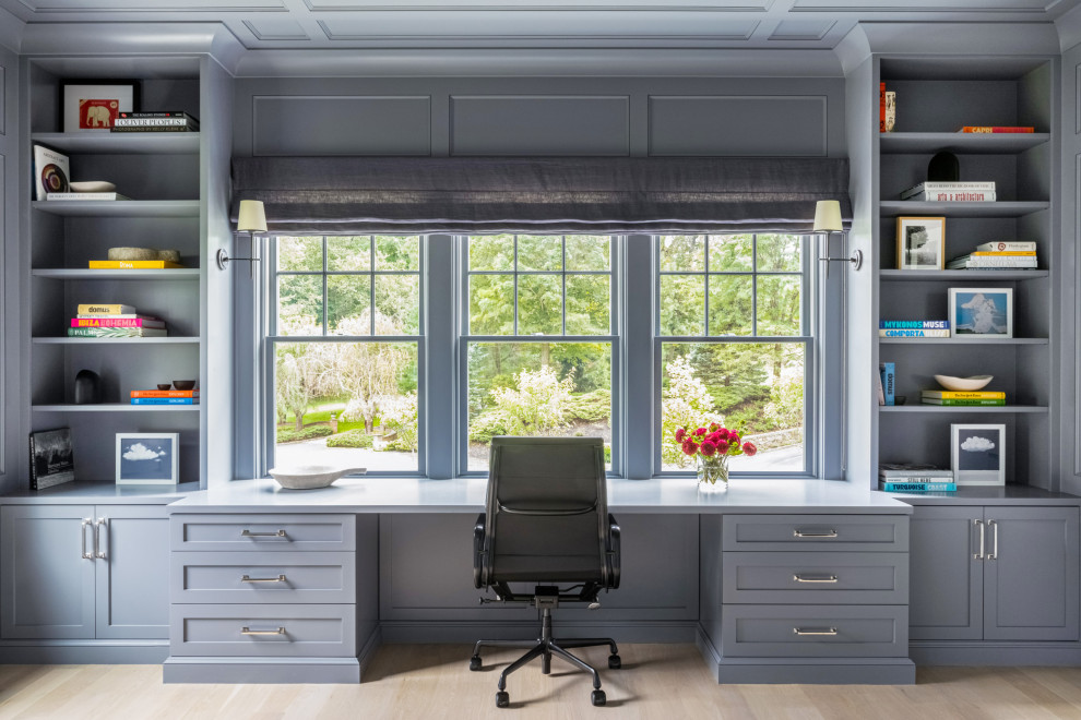 Imagen de despacho moderno con paredes azules, suelo laminado, escritorio empotrado, suelo marrón y todos los tratamientos de pared
