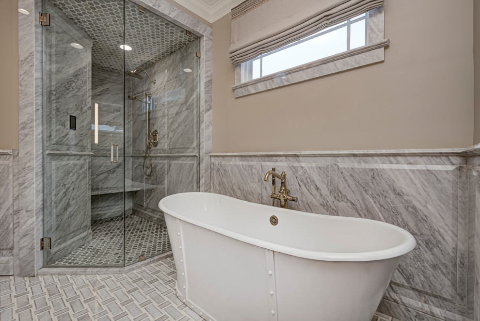 На фото: главная ванная комната в стиле фьюжн с душевой комнатой, серой плиткой, мраморной плиткой, бежевыми стенами, душем с распашными дверями, отдельно стоящей ванной и полом из керамогранита с
