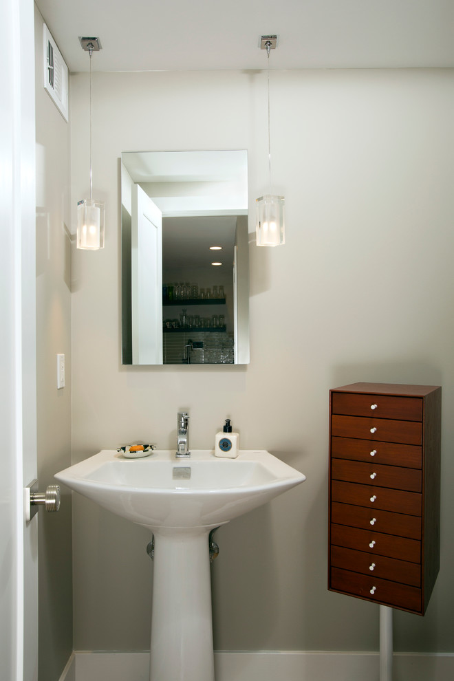 This is an example of a small modern powder room in DC Metro with a two-piece toilet, grey walls and a pedestal sink.