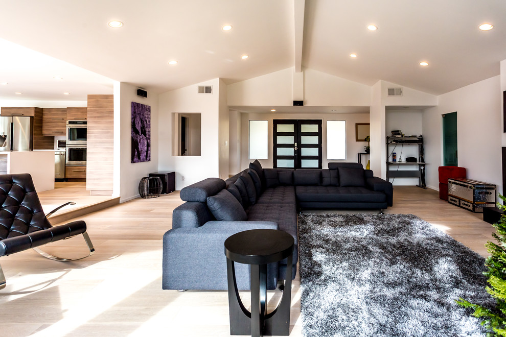 Photo of a large modern open concept living room in Los Angeles with white walls, light hardwood floors, a standard fireplace, a tile fireplace surround and a wall-mounted tv.