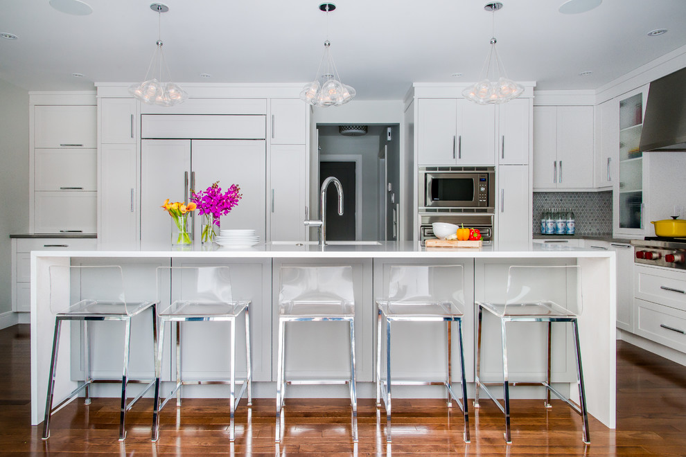 Eat-in kitchen - large transitional l-shaped medium tone wood floor and brown floor eat-in kitchen idea in Calgary with shaker cabinets, white cabinets, multicolored backsplash, mosaic tile backsplash, paneled appliances, an island, an undermount sink and quartz countertops