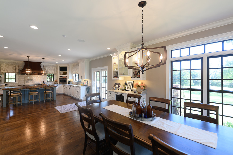 Inspiration for a large transitional l-shaped dark wood floor and brown floor kitchen remodel with an undermount sink, raised-panel cabinets, white cabinets, quartzite countertops, white backsplash, marble backsplash, stainless steel appliances and an island