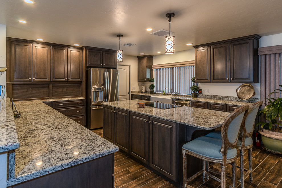 Large traditional u-shaped eat-in kitchen in Phoenix with a farmhouse sink, raised-panel cabinets, medium wood cabinets, granite benchtops, stainless steel appliances and with island.