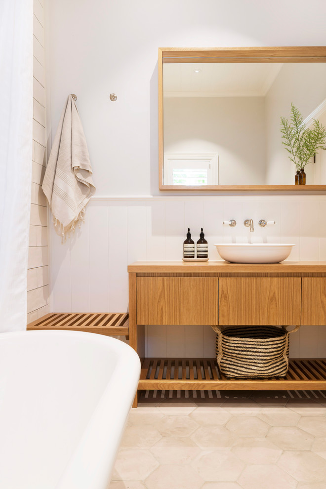 Photo of a country master bathroom in Wollongong with flat-panel cabinets, medium wood cabinets, a freestanding tub, white walls, a vessel sink, wood benchtops, beige floor and brown benchtops.