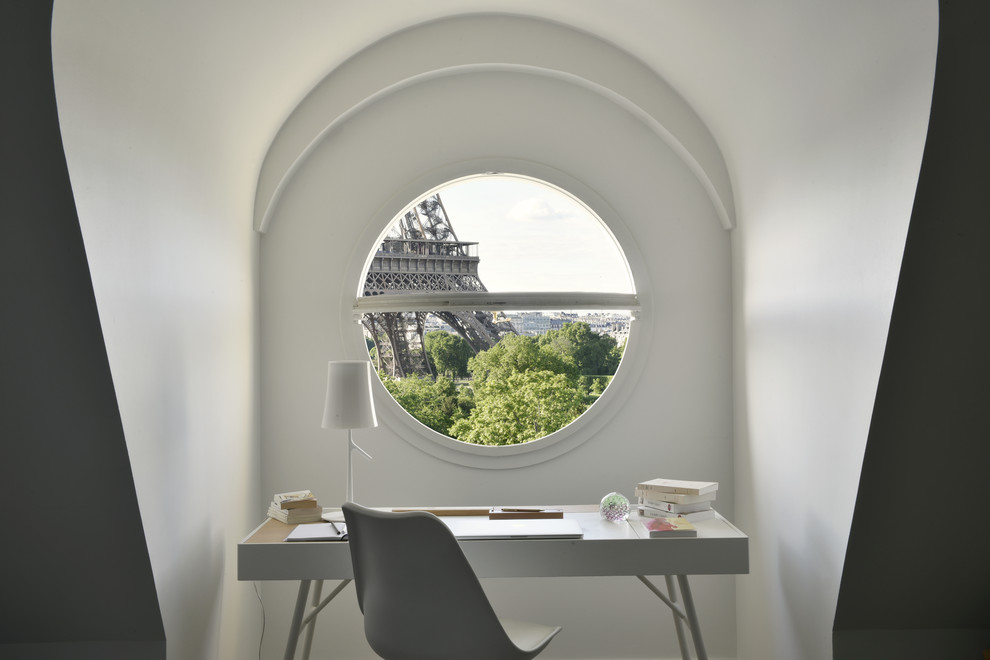 This is an example of a small contemporary home office in Paris with white walls and a freestanding desk.