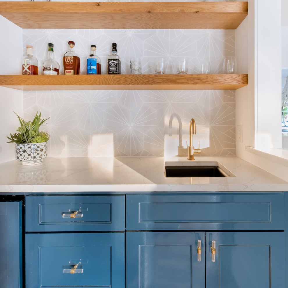 This is an example of a mid-sized contemporary home bar in Dallas with an undermount sink, shaker cabinets, blue cabinets, quartz benchtops, grey splashback, cement tile splashback, light hardwood floors and white benchtop.
