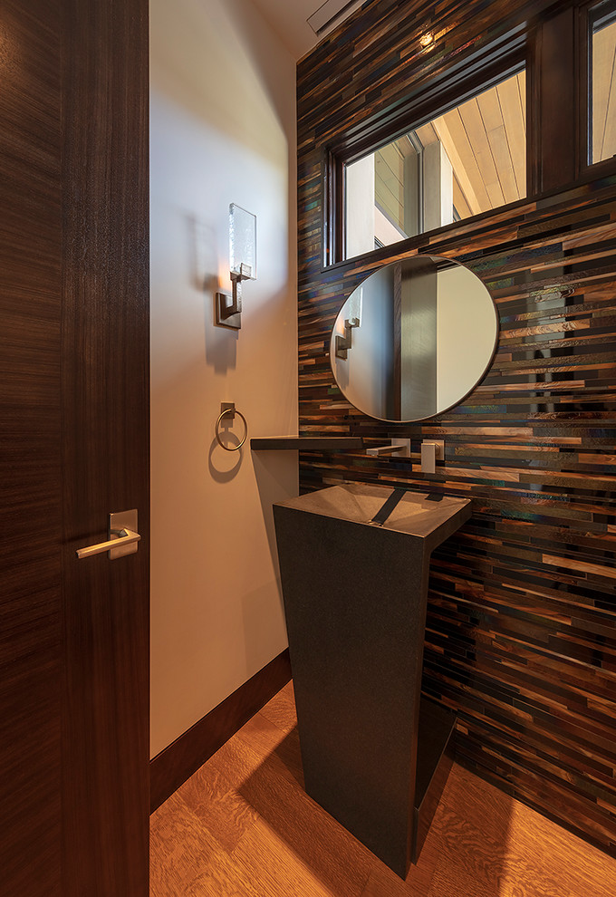 Photo of a contemporary powder room in San Francisco with brown tile, medium hardwood floors, a pedestal sink and brown floor.