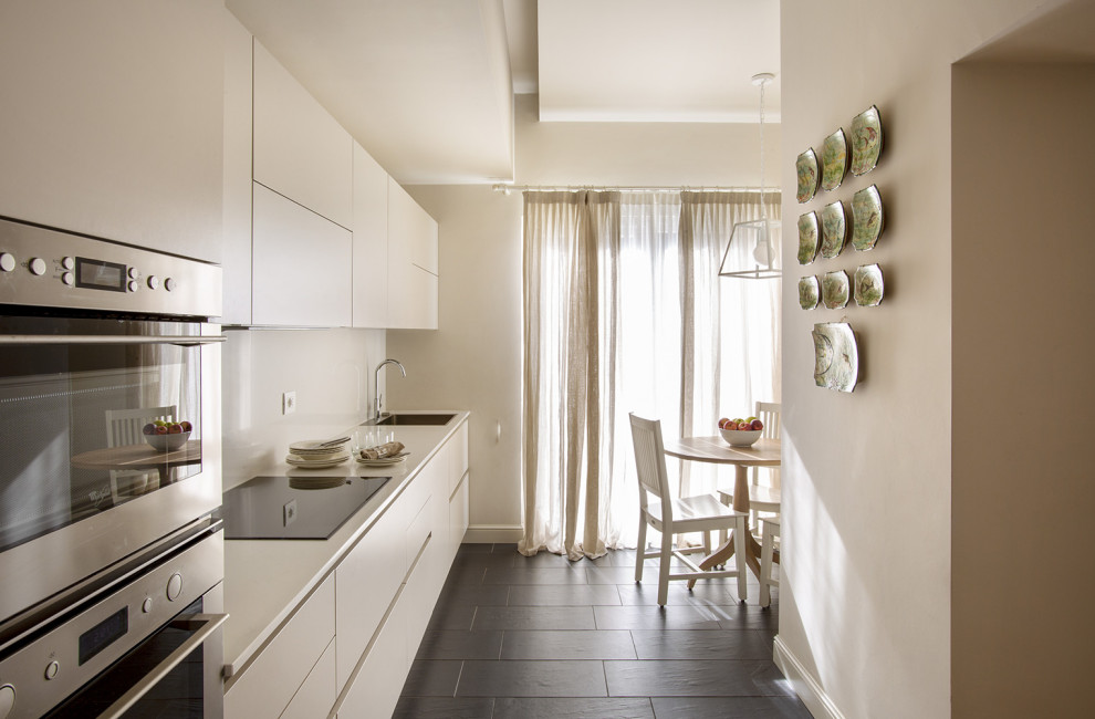 Medium sized classic single-wall enclosed kitchen in Milan with a built-in sink, flat-panel cabinets, beige cabinets, engineered quartz splashback, stainless steel appliances, slate flooring, black floors and a drop ceiling.