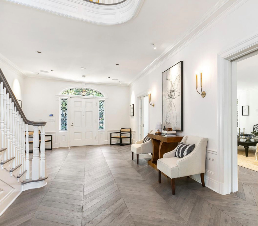 Großes Klassisches Foyer mit weißer Wandfarbe, hellem Holzboden, Einzeltür, weißer Haustür, grauem Boden und vertäfelten Wänden in Los Angeles