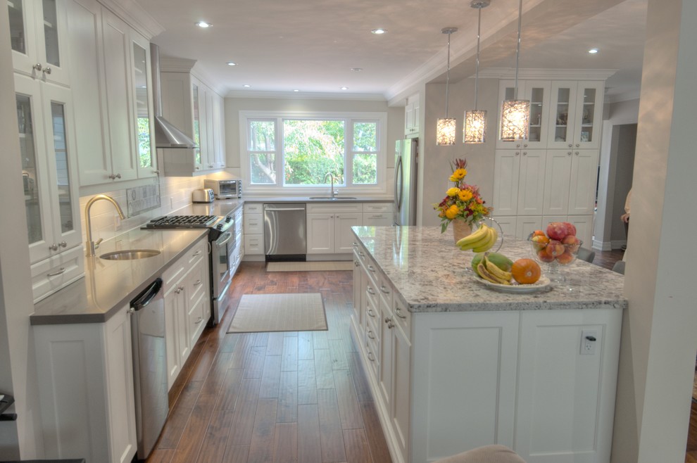 Large transitional u-shaped medium tone wood floor and brown floor eat-in kitchen photo in Toronto with a double-bowl sink, shaker cabinets, white cabinets, quartzite countertops, white backsplash, ceramic backsplash, stainless steel appliances and an island