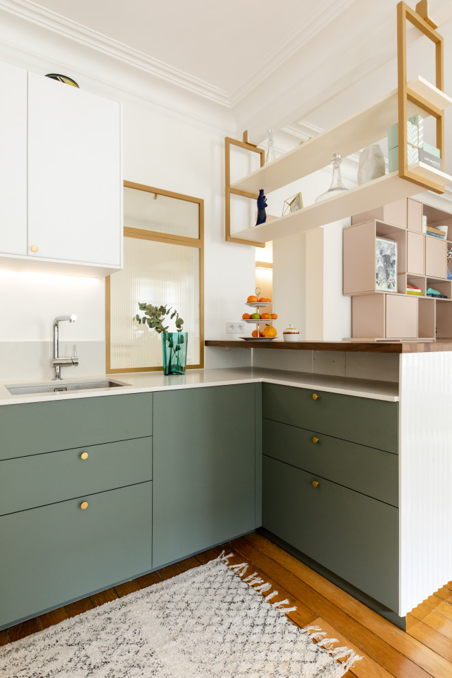 Inspiration for a contemporary l-shaped open plan kitchen in Paris with an undermount sink, flat-panel cabinets, green cabinets, medium hardwood floors, brown floor and beige benchtop.