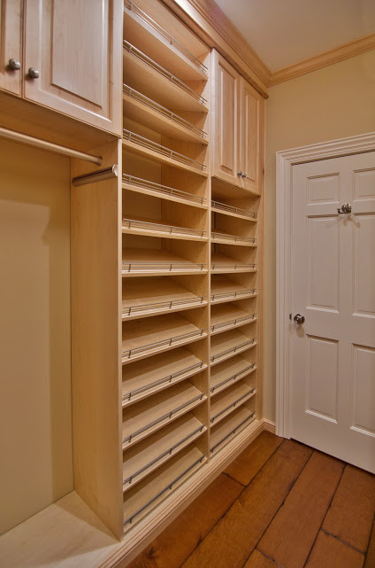 This is an example of a mid-sized traditional walk-in wardrobe in New York with raised-panel cabinets, light wood cabinets and dark hardwood floors.