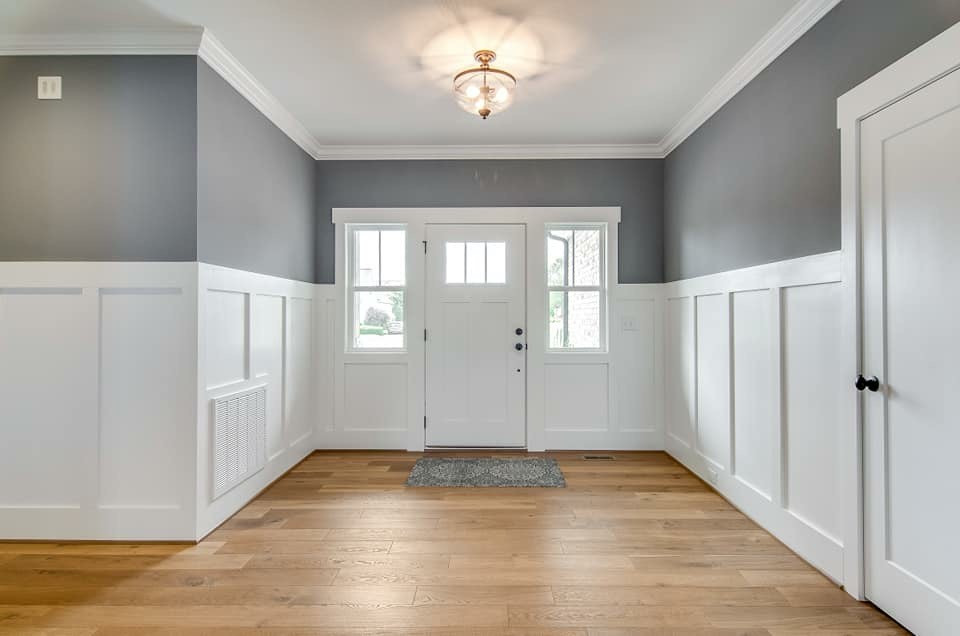 Exempel på en stor modern ingång och ytterdörr, med grå väggar, mellanmörkt trägolv, en enkeldörr, en vit dörr och flerfärgat golv