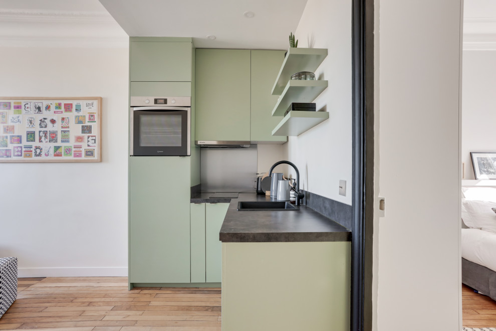 Design ideas for a small transitional l-shaped open plan kitchen in Paris with a single-bowl sink, beaded inset cabinets, green cabinets, no island, grey splashback, black appliances, medium hardwood floors and grey benchtop.