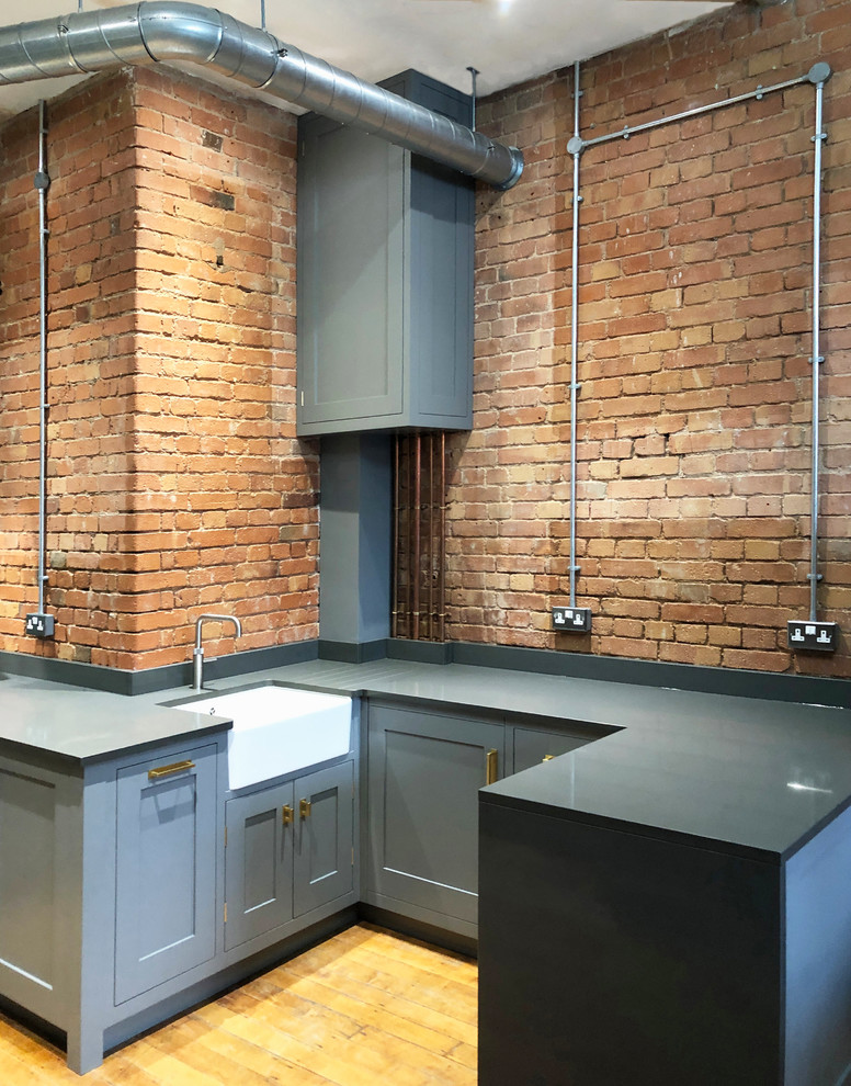 Small industrial l-shaped separate kitchen in Other with a farmhouse sink, shaker cabinets, grey cabinets, quartzite benchtops, blue splashback, ceramic splashback, stainless steel appliances, light hardwood floors and grey benchtop.