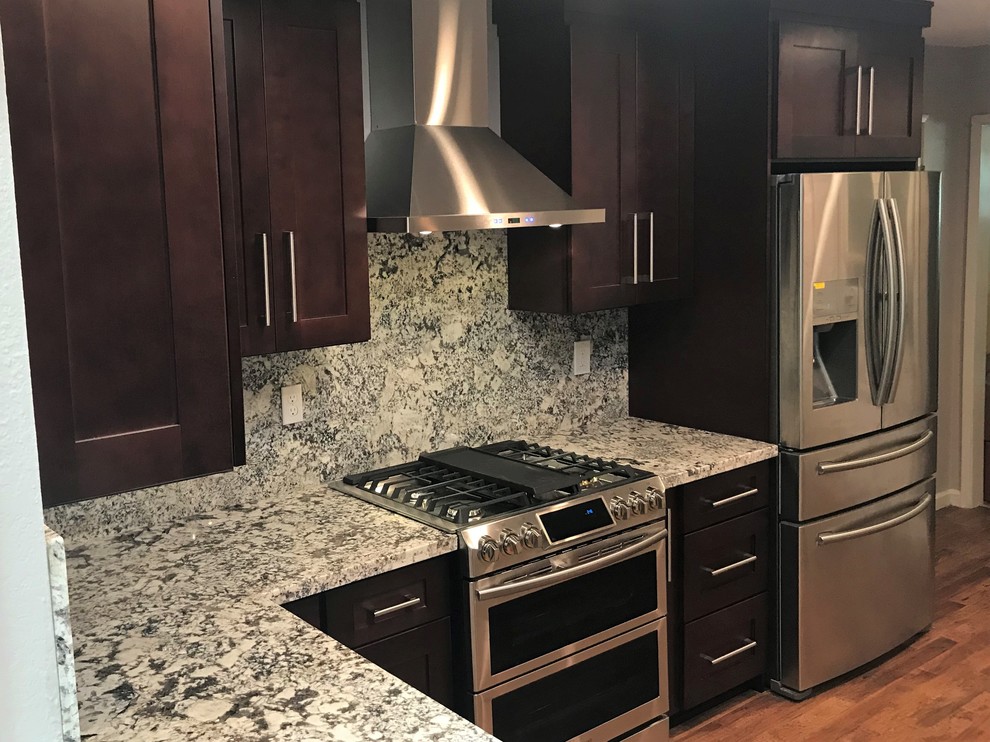 Example of a mid-sized transitional l-shaped light wood floor and brown floor eat-in kitchen design with an undermount sink, shaker cabinets, dark wood cabinets, granite countertops, multicolored backsplash, stone slab backsplash, stainless steel appliances, an island and multicolored countertops