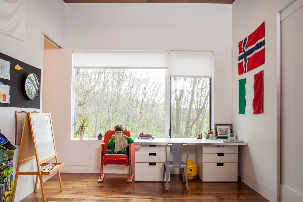 This is an example of a contemporary gender-neutral kids' playroom in Other with white walls and medium hardwood floors.