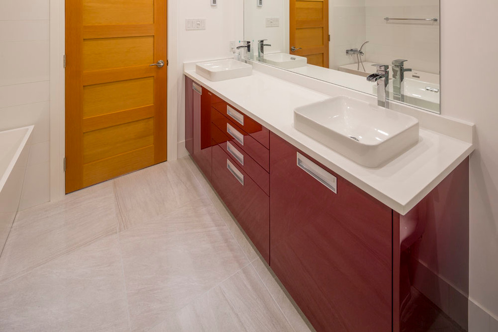 Design ideas for a mid-sized modern master bathroom in Vancouver with a vessel sink, red cabinets, engineered quartz benchtops, a drop-in tub, gray tile, porcelain tile, white walls, flat-panel cabinets, a corner shower, a one-piece toilet, laminate floors, grey floor and a hinged shower door.