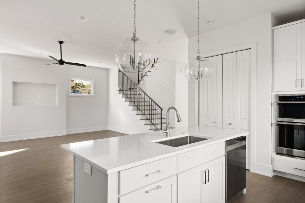 Open concept kitchen - large transitional u-shaped medium tone wood floor and brown floor open concept kitchen idea in Orlando with an undermount sink, shaker cabinets, white cabinets, marble countertops, white backsplash, porcelain backsplash, stainless steel appliances, an island and white countertops
