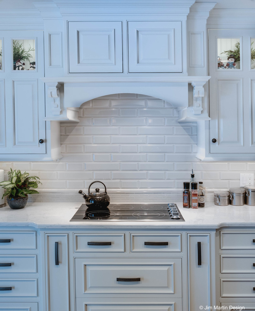 Mid-sized traditional l-shaped eat-in kitchen in Philadelphia with an undermount sink, raised-panel cabinets, white cabinets, quartzite benchtops, white splashback, ceramic splashback, stainless steel appliances, dark hardwood floors and with island.