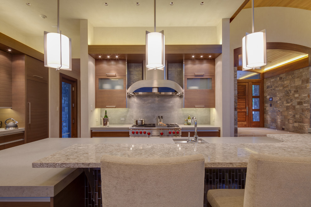 Inspiration for a transitional l-shaped eat-in kitchen remodel in Denver with an undermount sink, flat-panel cabinets, brown cabinets, gray backsplash, stone tile backsplash and paneled appliances