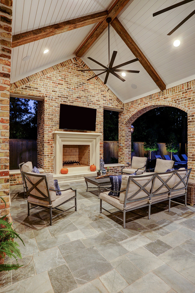 Inspiration for a mid-sized traditional backyard patio in Houston with an outdoor kitchen, natural stone pavers and a roof extension.