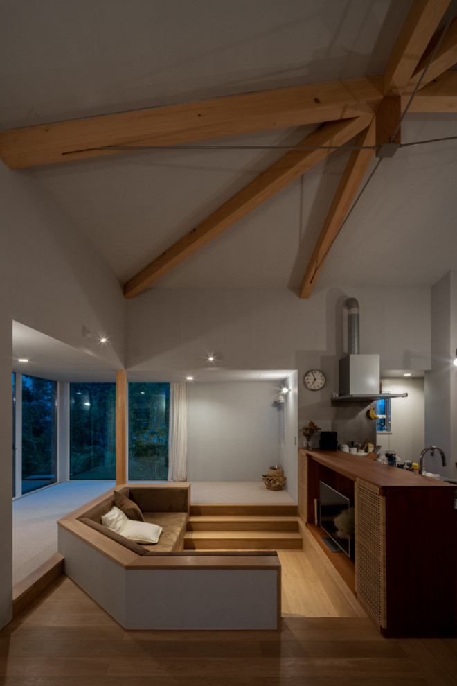 Mittelgroßes, Offenes Wohnzimmer ohne Kamin mit grauer Wandfarbe, Sperrholzboden, TV-Wand und freigelegten Dachbalken in Sonstige