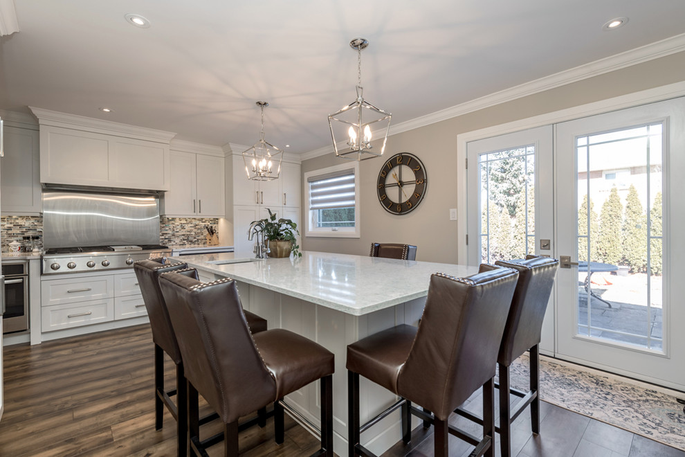 Inspiration for a large transitional galley dark wood floor and brown floor eat-in kitchen remodel with an undermount sink, shaker cabinets, white cabinets, quartz countertops, multicolored backsplash, mosaic tile backsplash, stainless steel appliances, an island and multicolored countertops