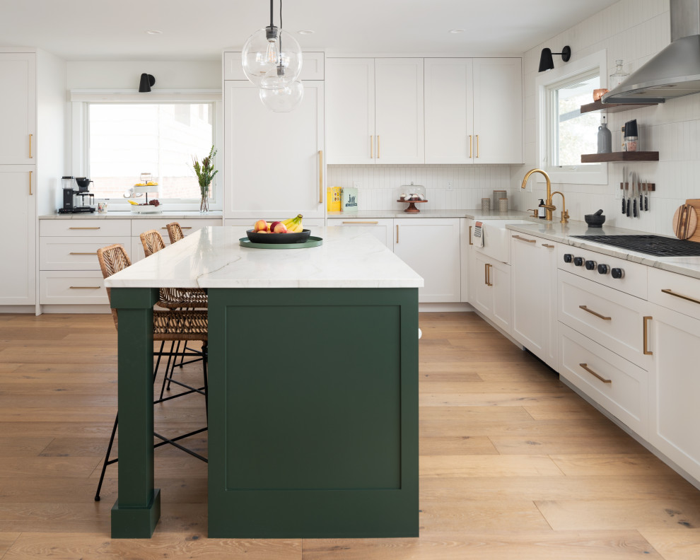 Inspiration for a modern l-shaped light wood floor kitchen remodel in Denver with a farmhouse sink, shaker cabinets, green cabinets, quartzite countertops, white backsplash, ceramic backsplash, stainless steel appliances, an island and white countertops